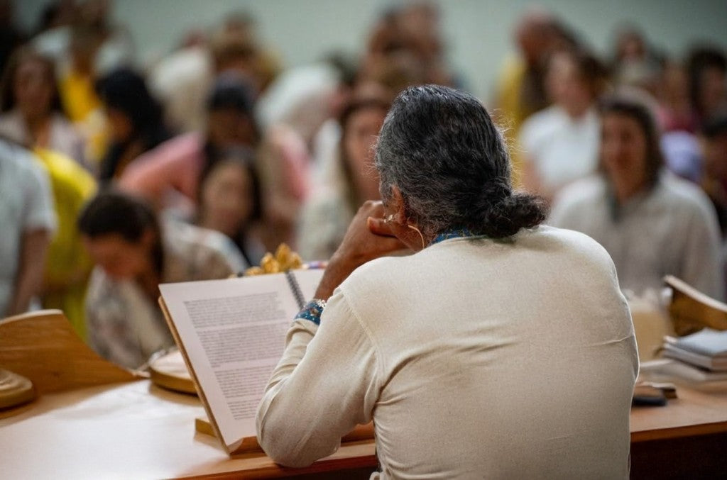 Paramahamsa Vishwananda in a white dress smiling while giving the lecture